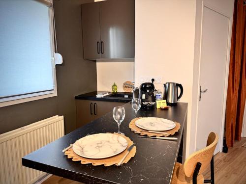 - une cuisine avec 2 assiettes et des verres à vin sur un comptoir dans l'établissement Le BraSeo, nice studio with parking in Rennes, à Rennes