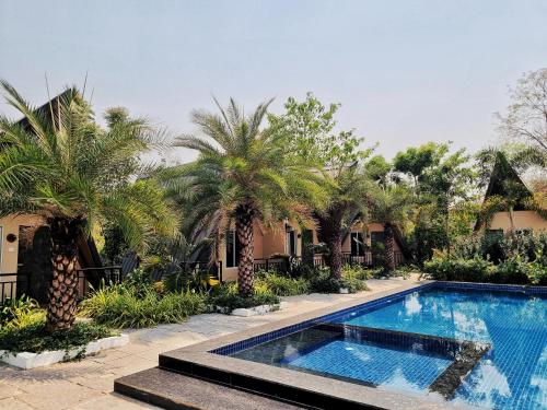 a swimming pool in front of a house with palm trees at Birds Nest Resort in Kinlivli