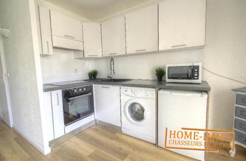 une cuisine avec un lave-linge et un micro-ondes dans l'établissement Charmant 2 pièces dans résidence avec piscine, à Vallauris