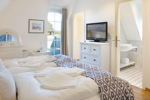 une chambre avec quatre lits blancs et une télévision dans l'établissement Senenskiin, à List auf Sylt