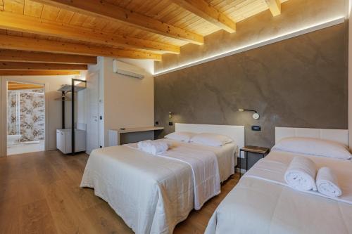 two white beds in a room with wooden ceilings at B&B Ca' Marognole in Caprino Veronese