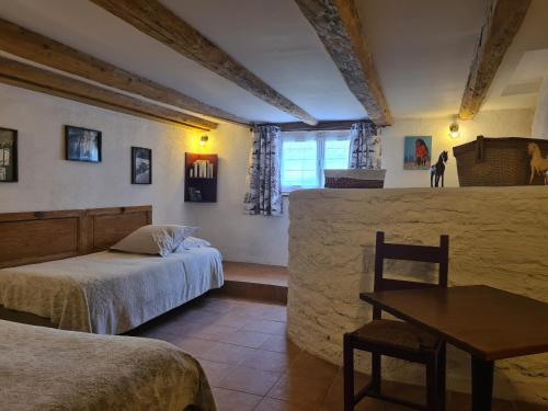 a bedroom with two beds and a table and a window at La maison d'antan in La Longeville