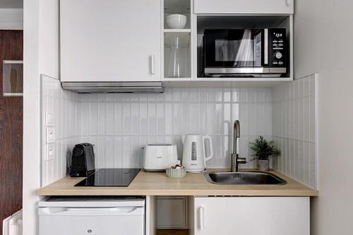 une cuisine avec un évier et un micro-ondes dans l'établissement Eiffel residence Apolline, à Paris