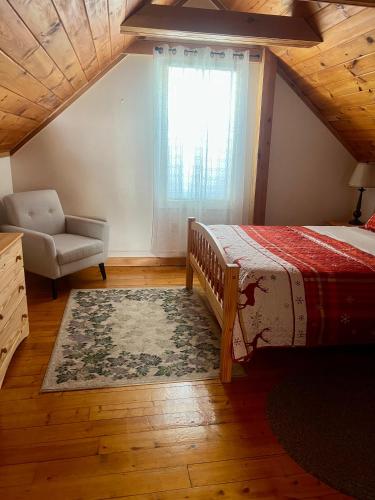 a bedroom with a bed and a chair and a window at Allegory Inn in Twin Mountain