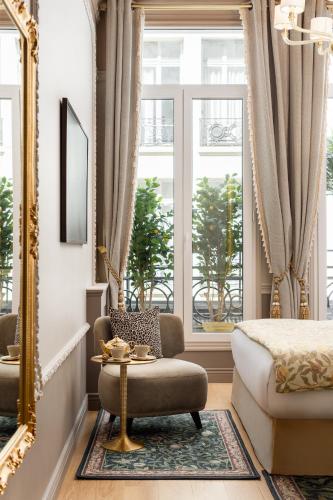une chambre avec un lit, une chaise et un miroir dans l'établissement The Donatella Suite - Champs Elysées, à Paris