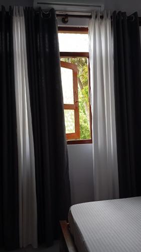 a bedroom with a bed and a window at Skyline & bitcoin coffee lodge in Kalutara