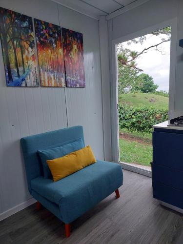 a blue chair with a yellow pillow in a room with a window at Cabaña Tesoro Escondido in Guápiles