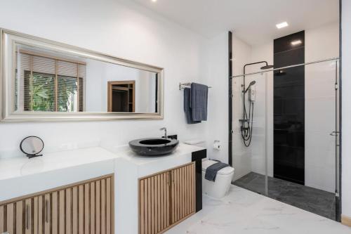 a bathroom with a sink and a toilet and a mirror at Villa Lom Talay - Family Retreat in Ban Thong Phlu