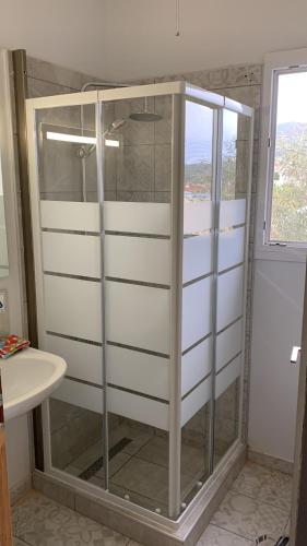 a glass shower in a bathroom with a window at La Bandolaise à Perdika in Perdika