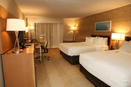 a hotel room with two beds and a desk at enVision Hotel & Conference Center Mansfield-Foxboro in Mansfield