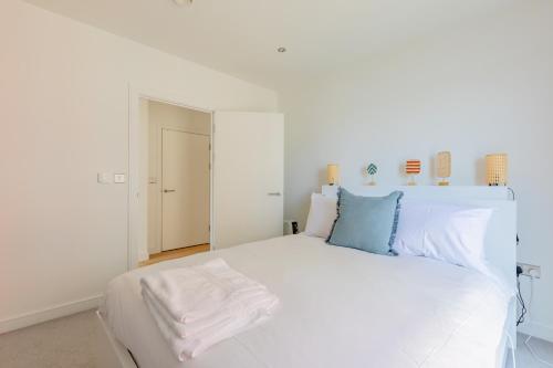 a white bedroom with a large white bed with blue pillows at Gorgeous 1Bd Flat with incredible views of the O2 in London