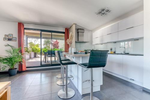 une cuisine avec des placards blancs et des tabourets de bar verts dans l'établissement GuestReady - Chic Stay with Jacuzzi and Parking, à Lyon