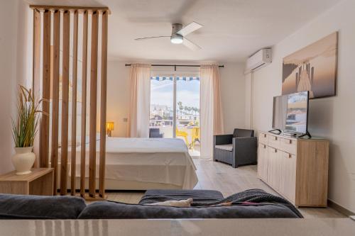 ein Schlafzimmer mit einem Bett, einem Fernseher und einer Couch in der Unterkunft Modern studio with ocean views and heated pool in Malibu Park in Adeje