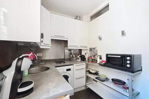 une cuisine avec des armoires blanches et un micro-ondes dans l'établissement Charming apartment near the Eiffel Tower, à Paris