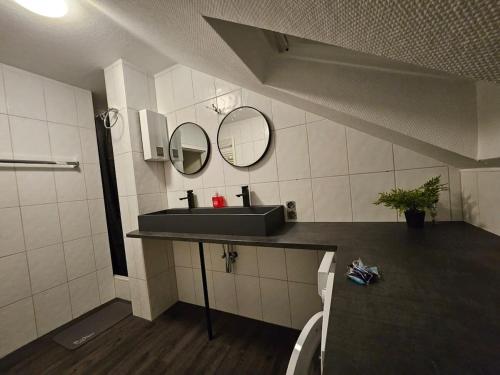 a bathroom with a sink and two mirrors on the wall at Ruhrpott Serviced Apartments in Recklinghausen