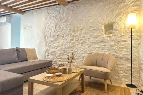 un salon avec un canapé et une chaise dans l'établissement Au fil de l’eau A cozy nest in the heart of the city, à LʼIsle-sur-la-Sorgue