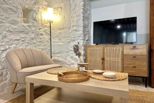 - un salon avec une table, une chaise et une télévision dans l'établissement Au fil de l’eau A cozy nest in the heart of the city, à LʼIsle-sur-la-Sorgue