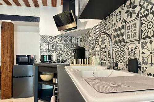 - une cuisine avec du carrelage noir et blanc sur le mur dans l'établissement Au fil de l’eau A cozy nest in the heart of the city, à LʼIsle-sur-la-Sorgue