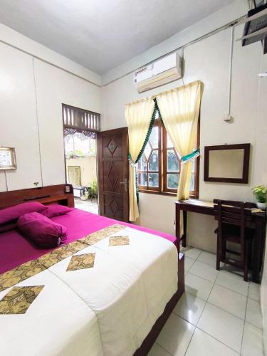 DemanganGaruda Syariah Homestay By Reccoma的一间卧室，配有一张床、一张书桌和一扇窗户