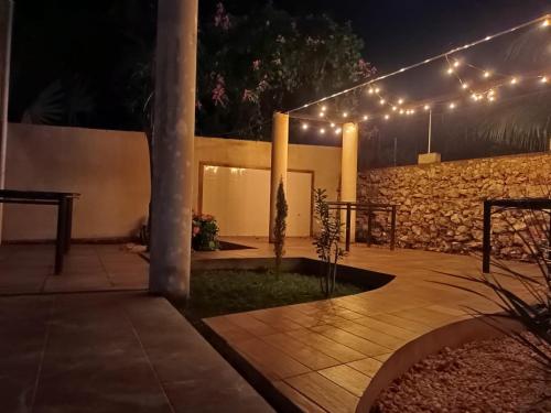 a patio with lights and a stone wall at night at Hotel 230 Valladolid in Valladolid