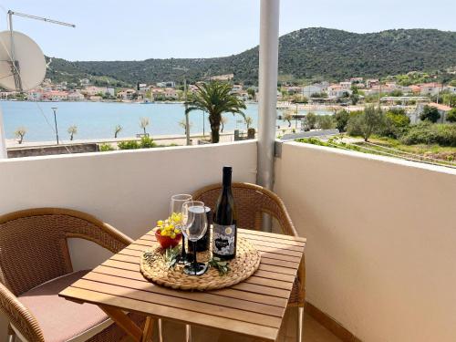 a table with a bottle of wine and flowers on a balcony at Apartment Natasa in Vinišće