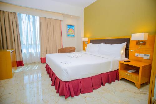 a bedroom with a large white bed with a red skirt at Holiday Inn Dar Es Salaam by IHG in Dar es Salaam