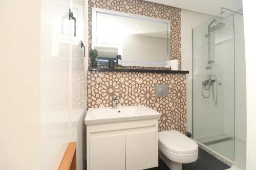 a bathroom with a toilet and a sink and a mirror at HE Appart 402 situé à Bonapriso hôtel de l'air avec salle de Gym in Douala