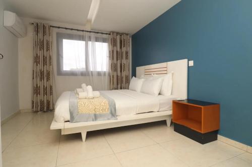 a bedroom with a white bed and a window at HE Appart 402 situé à Bonapriso hôtel de l'air avec salle de Gym in Douala