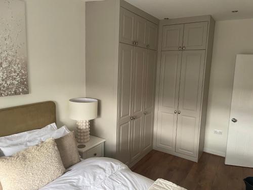 a bedroom with a bed and a cabinet and a lamp at Night Owl Cottage in Rainford