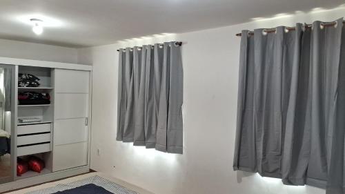 a room with white walls and gray curtains at CABO FRIO, SUITES PÉ AREIA in Cabo Frio