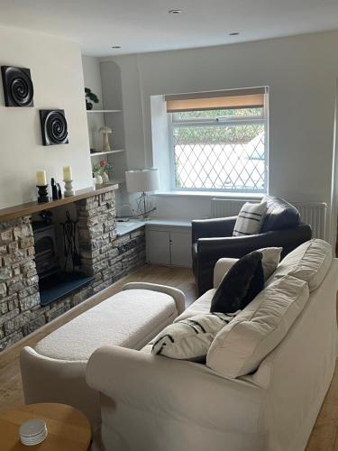 Night Owl Cottage في Rainford: غرفة معيشة مع أريكة بيضاء ومدفأة