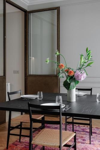 une table noire avec des chaises et un vase de fleurs dans l'établissement A mini-suite for 2, in a green setting, à Paris