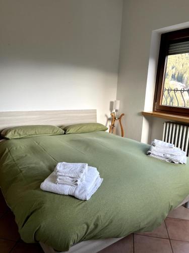 a green bed with two towels on top of it at Appartamento Candido Dolomiti CEDANOSTRA in Candide