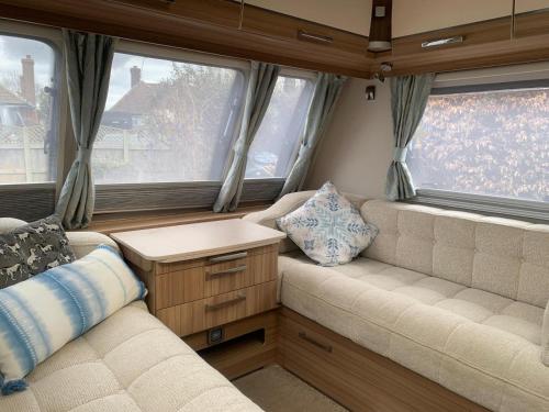 a living room with a couch and two windows at Country Roost in High Wycombe