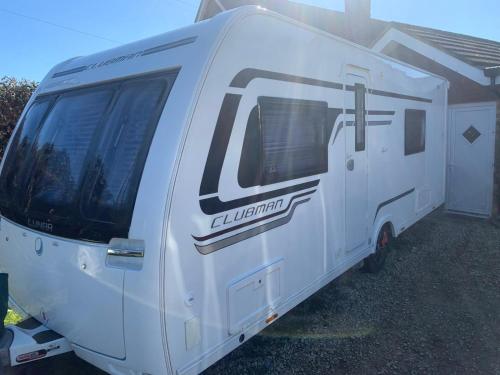 a white caravan parked in front of a house at Country Roost in High Wycombe