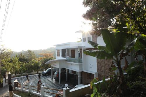 a white house with people standing in front of it at Periyar Homes Plantation Stay in Thekkady