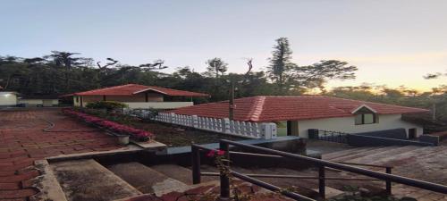 a house with a fence and flowers in front of it at Rushika Homestay Chikmagalur in Chikmagalūr