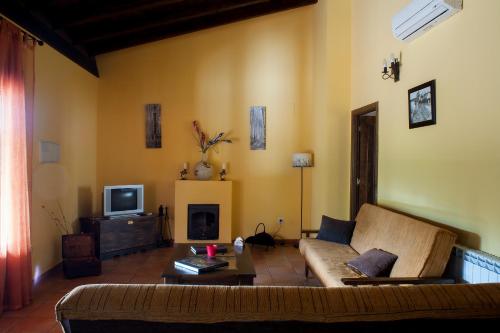 a living room with a couch and a tv at Ramajal Rural in Horcajo