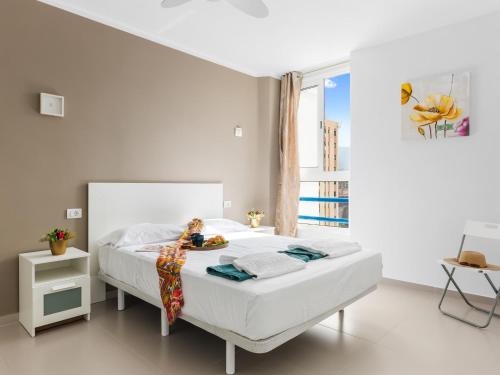 ein weißes Schlafzimmer mit einem großen weißen Bett und einem Fenster in der Unterkunft Wonderful Attic in Playa Paraiso in Playa Paraiso