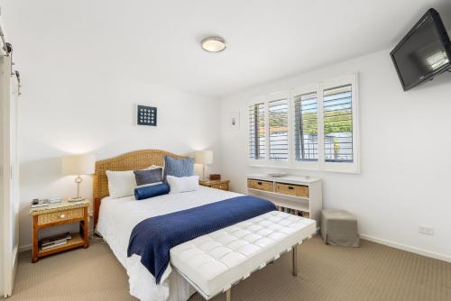 a white bedroom with a bed and a tv at Orford Coastal Retreat by Peppy Beach Retreats in Orford