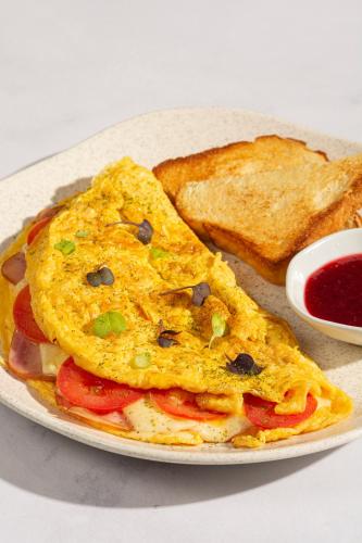a plate with an omelet and two pieces of toast at Wellcomm Spa & Hotel in Medellín