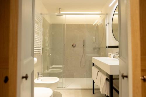a white bathroom with two sinks and a shower at Hotel Casa Bianconi in Norcia