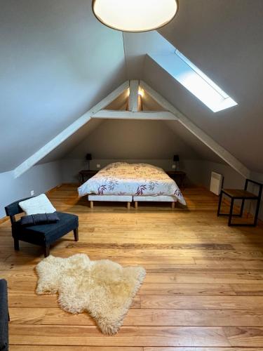 Cette chambre mansardée comprend un lit et un tapis. dans l'établissement Domaine de la Ferme de Fourges, à Flancourt-Crescy-en-Roumois