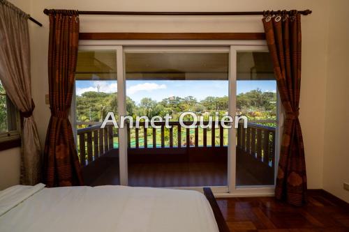 Un dormitorio con una cama y un balcón con ventana. en 4 Bedroom Cabin in Camp John Hay, en Baguio