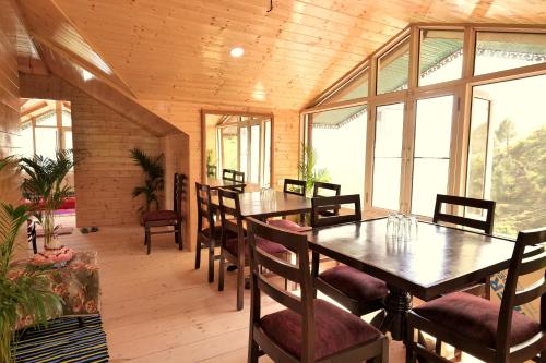 チェイルにあるAarambh - A Boutique Homestay By Shivaneel Hospitalityのテーブルと椅子と窓のあるダイニングルーム
