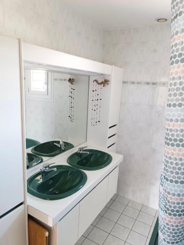 La salle de bains est pourvue de 2 lavabos verts et d'un miroir. dans l'établissement Maison - Piscine Parking Wifi - CLG Savoie, à Cruet