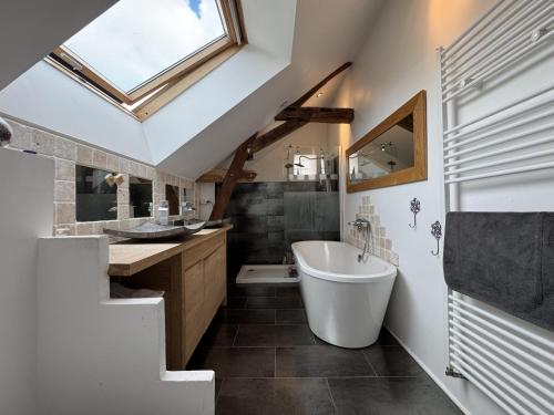 a bathroom with a large tub and a sink at La Parenthèse Verte - 8pers - Piscine - Rêve au Mans in Roézé-sur-Sarthe