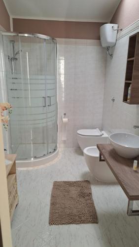 a bathroom with a shower and two sinks and a toilet at Villa Teresa in Oschiri