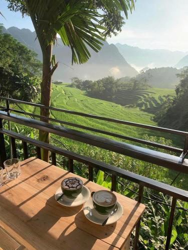 a wooden table with two bowls and plates on top of a hill at Puluong Aroma in Hương Bá Thước
