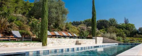 une piscine avec des chaises et des arbres en arrière-plan dans l'établissement La Bastide - Le Grenache - Le Syrah au Domaine Chateau Henri Bonnaud, au Tholonet
